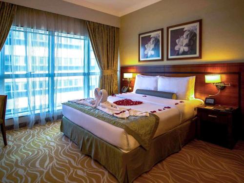 a hotel room with a bed and a large window at Grand Mercure Majlis Residences Abu Dhabi in Abu Dhabi