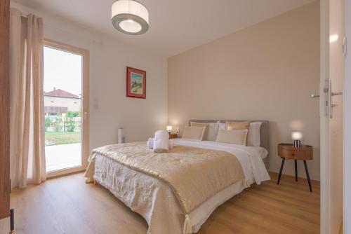 a white bedroom with a large bed and a window at Villa au coeur de Mézériat in Mézériat