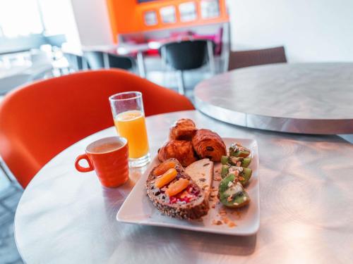 ibis Styles Paris Velizy في فيليزي-فيياكوبليه: طبق طعام على الطاولة مع كوب من عصير البرتقال