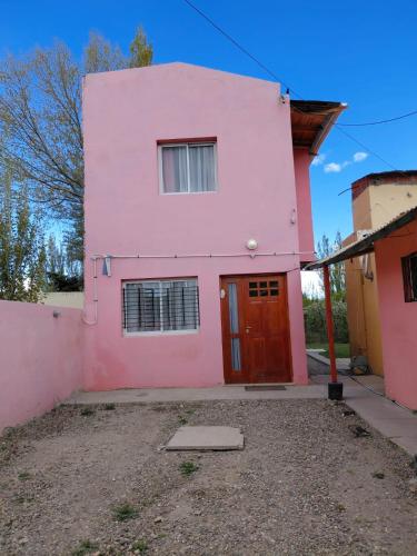 una casa rosa con puerta roja en Refugio del Viento, en Gobernador Gregores