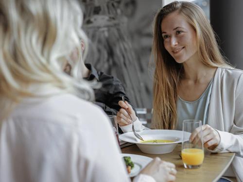 Duas mulheres sentadas à mesa a comer comida. em Mercure Hotel Koeln Belfortstrasse em Colónia