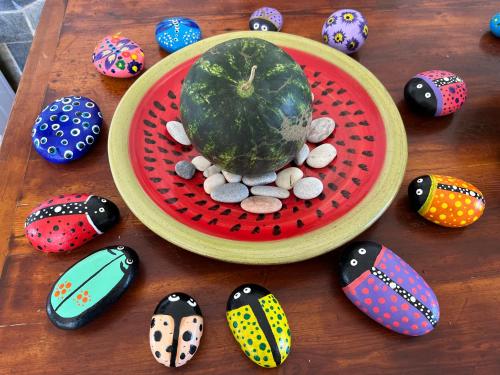 a wooden table with a plate of rocks and a bowl of watermelon at Σπιτάκι στον κήπο in Rafina