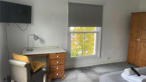 a bedroom with a window and a desk and a chair at Golden Triangle Rooms in Norwich
