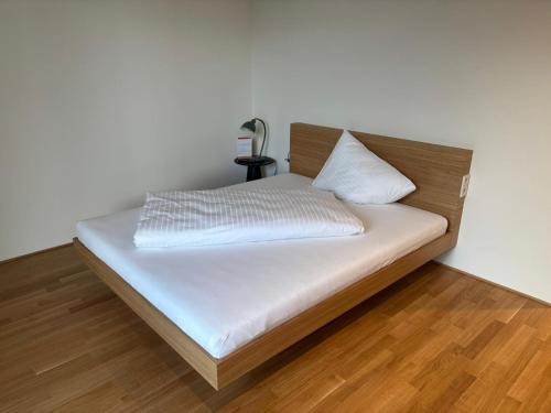a bed with white sheets and a wooden headboard at Herburger Living in Dornbirn