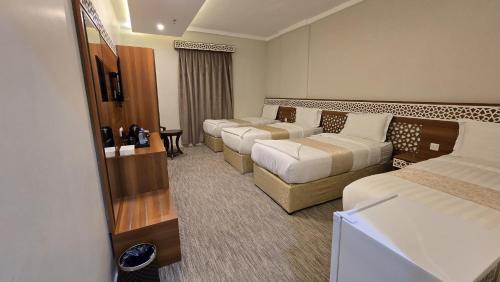 une chambre d'hôtel avec trois lits et un canapé dans l'établissement فندق كنوز العنود مكة للغرف والأجنحة الفندقية - Knoz Al Anood Hotel Makkah for Hotel Rooms and Suites, à La Mecque
