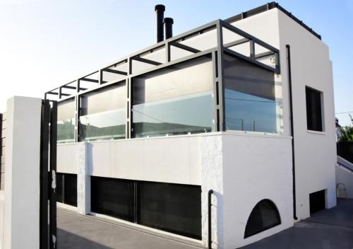a white house with large glass windows at White & Black Aegina - Private Garden & Parking in Áyioi Asómatoi