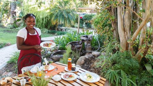 uma mulher segurando um prato de comida em uma mesa em GuBas De Hoek meet eat sleep em Robertson