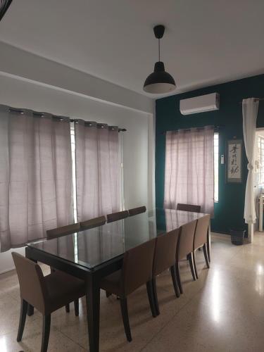Un comedor con una mesa de cristal y sillas. en A Borneo Guesthouse, en Johor Bahru