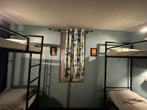 a room with three bunk beds and a window at The Backpacker Storey in Kangra