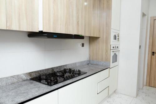 a kitchen with white cabinets and a stove top oven at Luxury 3BR Apt w balcony view in Chevron, Lekki in Lekki