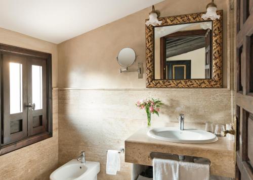 a bathroom with a sink and a mirror and a toilet at Hotel Casa 1800 Granada in Granada