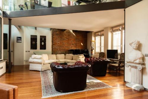Il comprend un salon doté d'un mobilier en cuir et d'un mur en briques. dans l'établissement YouHosty - Luxury Town House, à Milan