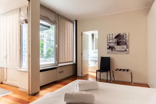 a bedroom with a bed and a chair and windows at YouHosty - Luxury Town House in Milan