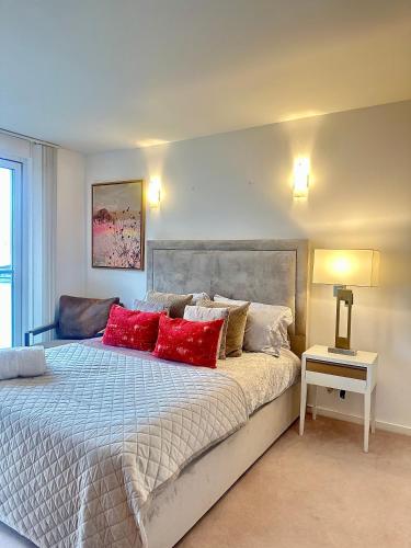a bedroom with a large bed with red pillows at Luxury apartment in Canary Wharf in London