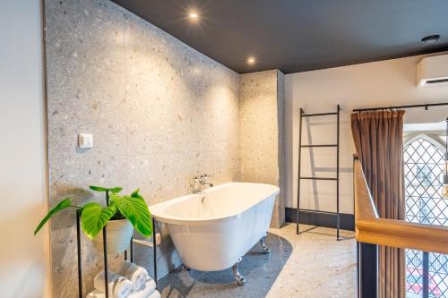 a bathroom with a tub and a plant in it at Crescent Place by Mansley in Cheltenham