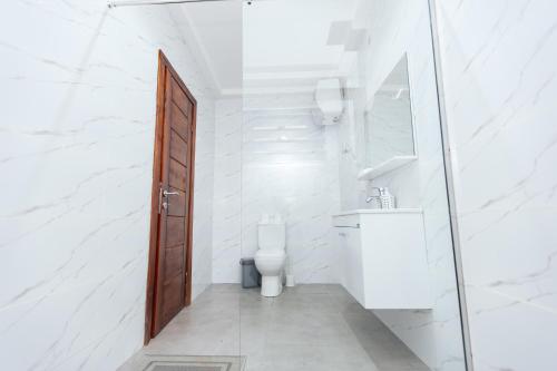a white bathroom with a toilet and a sink at Luxurious townhouse behind Achimota Mall in Accra