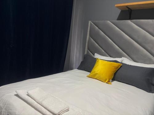 a white bed with a yellow pillow on it at Ruros Guest House in Kempton Park