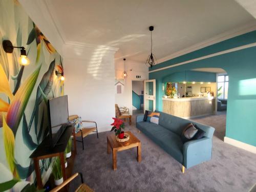 a living room with a blue couch and a tv at Beach Hotel Torbay B&B in Paignton