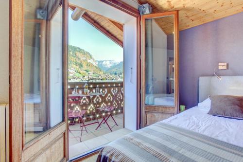 Un dormitorio con una cama y un balcón con vistas. en Mas Verjus, en Morzine