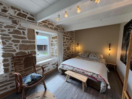 a bedroom with a bed and a stone wall at Ty Guillerm - Maison bretonne entre terre et mer in Plounévez-Lochrist