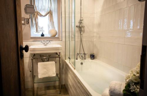 une salle de bain avec une baignoire, un lavabo et une douche dans l'établissement The Old Pen Cottage, à Leafield