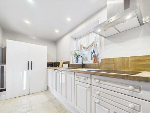 une cuisine avec des armoires blanches et un évier dans l'établissement The Old Pen Cottage, à Leafield