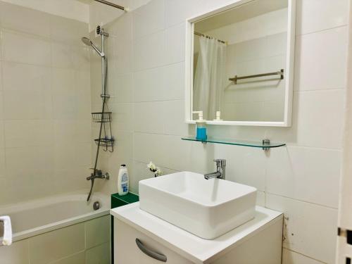 Un baño blanco con lavabo y bañera. en Holiday Apartment 01, en Aubervilliers