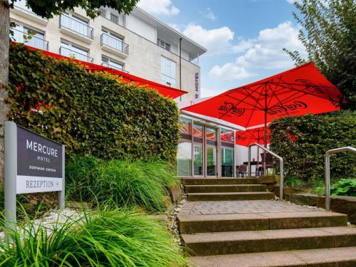 a building with a red umbrella next to a building at Mercure Hotel Dortmund Centrum in Dortmund