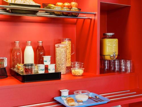 Un estante rojo con muchas botellas y cuencos de comida. en hotelF1 Cholet, en Cholet