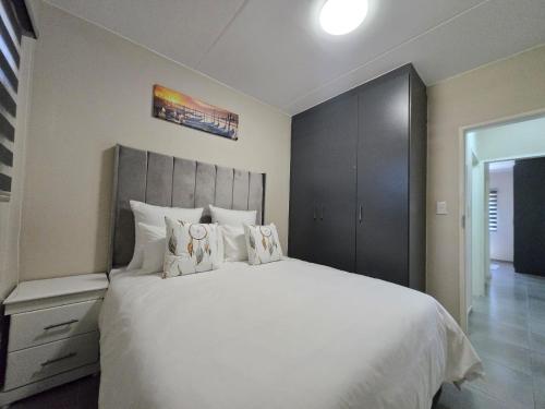 a bedroom with a large bed with white sheets and pillows at Nat's Villa in Midrand