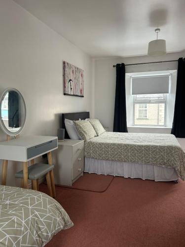 a bedroom with two beds and a desk and a mirror at Central Town House,Moville 61 in Moville