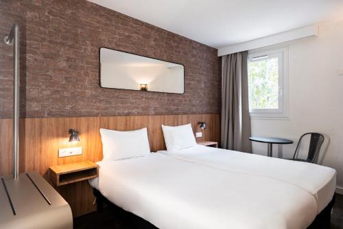 Un pat sau paturi într-o cameră la Ibis Styles Lyon Villeurbanne Parc de la Tête d'Or