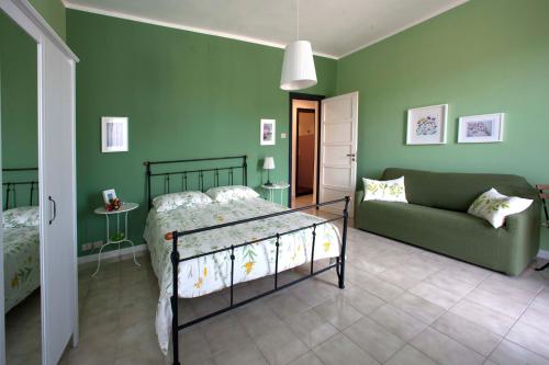 a bedroom with green walls and a bed and a couch at La Casa di Nonna Concettina in Modica