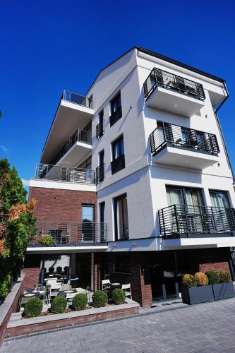 a white building with tables and chairs in front of it at Madera apartments in Čačak