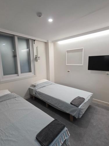 a room with two beds and a flat screen tv at 가가하우스 을지로 in Seoul
