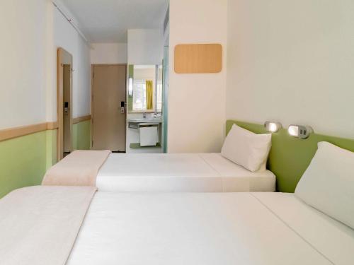 two beds in a small room with a bathroom at ibis budget Sao Paulo Paraiso in Sao Paulo
