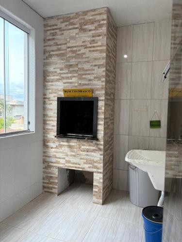 a bathroom with a fireplace with a flat screen tv at apartamento lindo com 2 quartos in Itapoa