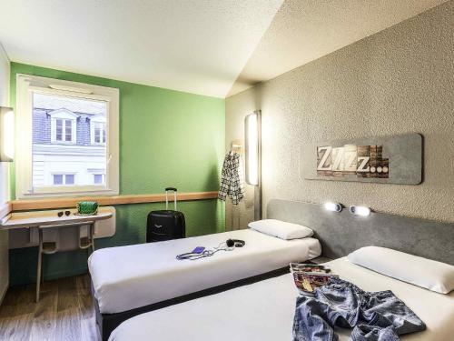 a hotel room with two beds and a desk at Ibis Budget Lille Gares Vieux-Lille in Lille