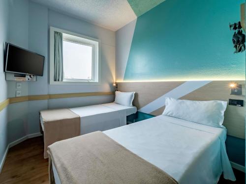 a small room with two beds and a tv at ibis budget Sao Paulo Jardins in Sao Paulo