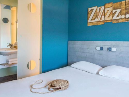 a bedroom with a bed with a hat on it at ibis budget Pertuis Portes du Luberon in Pertuis