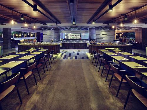 a dining room with tables and chairs in a restaurant at Mercure Bali Legian in Legian
