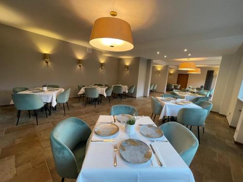 una sala da pranzo con tavoli bianchi e sedie blu di Hotel Balduin - Natur & Flussblick a Balduinstein