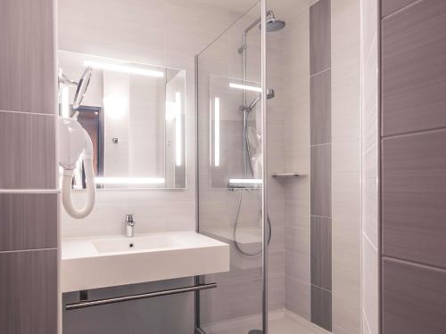 a white bathroom with a sink and a shower at Mercure Trouville Sur Mer in Trouville-sur-Mer