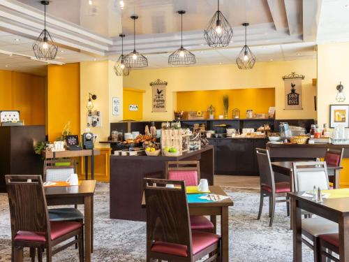 トゥルヴィル・シュル・メールにあるメルキュール トゥルーヴィル シュル メールのテーブルと椅子のあるレストランとカフェテリア