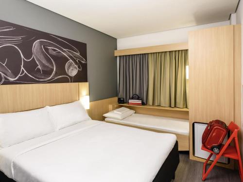 a hotel room with two beds and a red chair at ibis Recife Aeroporto in Recife
