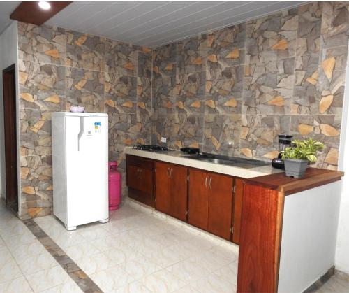 cocina con nevera blanca y pared de piedra en CASA VACANZA Cenaida Mono Titi, en Leticia