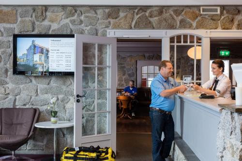 two men standing at a counter in a bar at Dolmsundet Hotell Hitra in Melandsjøen