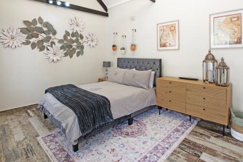 a bedroom with a bed and a wooden dresser at The Pillans Manor Studio in Cape Town