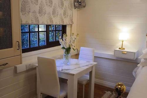 a dining room table with white chairs and a vase of flowers at 1 Bed Lodge - Southampton - Sleeps 2 - Parking in Southampton