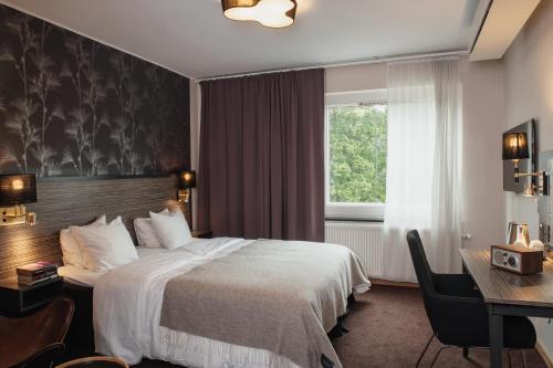 a hotel room with a bed and a desk and a window at Home Hotel Slottsparken in Linköping